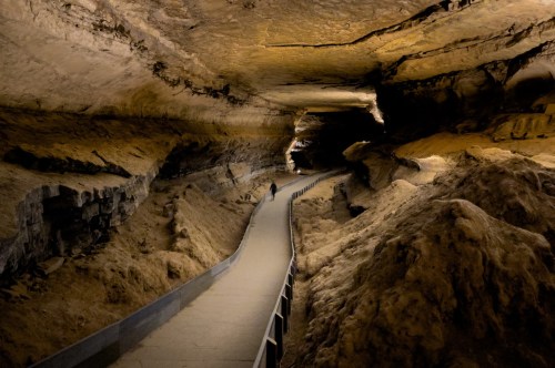 A person walking down a long and massive corridor underground.