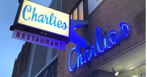 Vintage blue neon 'Charlie's' sign on a brick building with bold font below. Nostalgic, inviting restaurant charm.