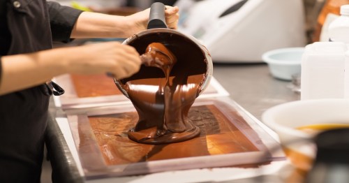 liquid chocolate being poured onto a pan at a confectionary shop