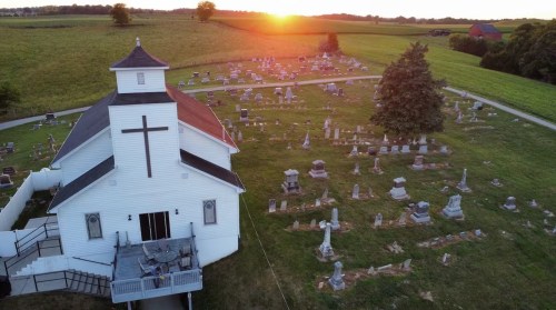 The sun sets beyond a white church Airbnb with its own graveyard in Kingston, Ohio.
