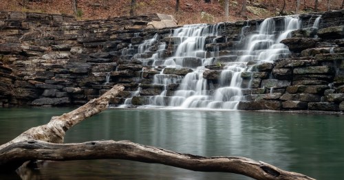 waterfall over rocks that leads into a small lake in devil's den state park in arkansas