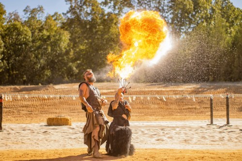 Viking Festival in Arkansas showing two characters dressed up in traditional Viking clothing blowing fire while one holds a torch