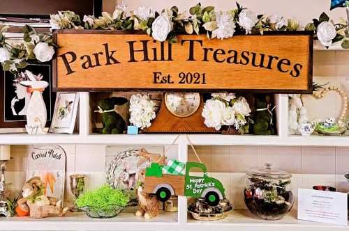 A shelf with decorative items inside an antique store in Denver with a large wooden sign that reads Park Hill Treasures