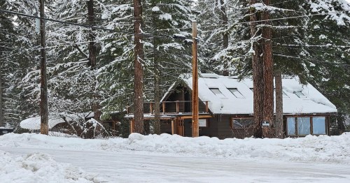 a wooden cabin covered in snow nearby forest trees in idaho