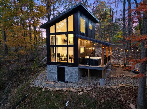 A unique asymmetrical cabin with floor-to-ceiling windows is surrounded by fall foliage in Laurelville, Ohio.
