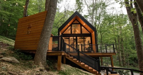 a black wooden cabin with soft orange and yellow lighting in the woods of north carolina