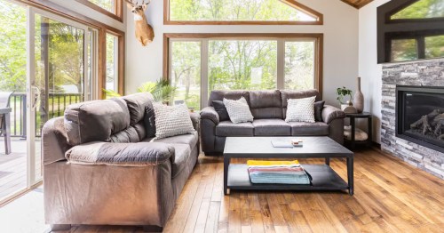 Bright room with vaulted wood ceilings, large windows, leather sofas, and a stone fireplace.
