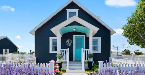 A whimsical blue cottage with an octopus decoration near the door, surrounded by a field of purple flowers.
