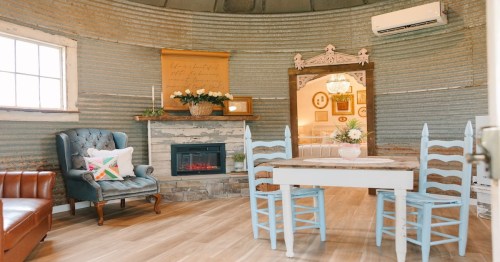 cozy and quaint interior of a silo home with a dining table, doorway, side chair, and fireplace