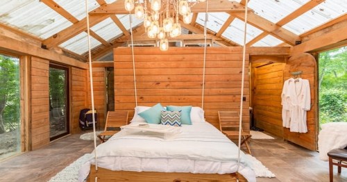 large queen bed with white sheets and blue pillows in a wooden cabin in texas