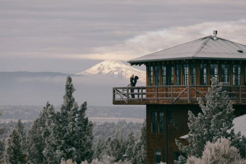 three story cabin with forest trees and a snowy mountain in the background