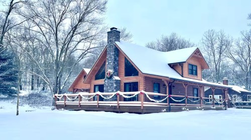 A scenic snow-covered cabin adorned with wreaths sits among a still landscape in Howard, Ohio.