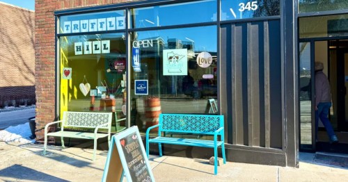 A sign stands on a sidewalk in front of the entrance to a chocolate shop in Minnesota. A sign in the window spells out "Truffle Hill"