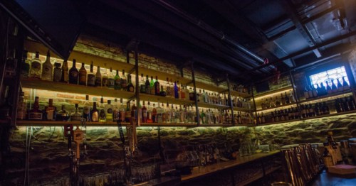 Hundreds of liquor bottles line the shelves of a bar at the Bramhall Restaurant in Portland, Maine. The lighting is very dim.