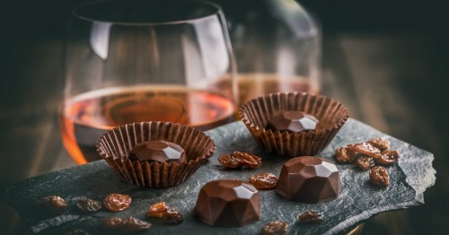 chocolate pralines on a black counter with a glass on wine in the background