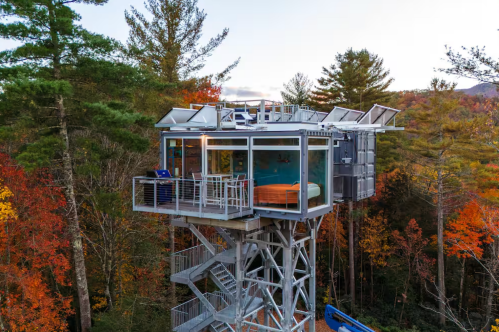 Exterior of lookout tower Airbnb made from two shipping containers surrounded by trees.