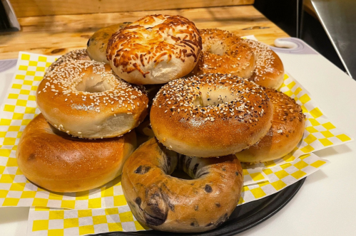Yellow and black tray covered with several types of bagels