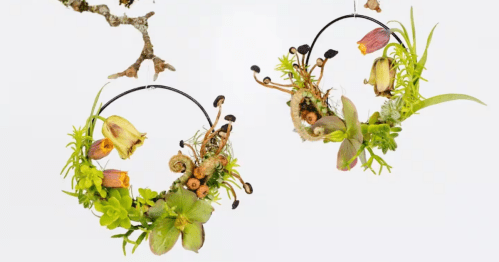 Against a white background, a pair of hoop ornaments are sculpted with delicate flowers.