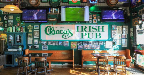 Wide view of Clancy's Irish Pub bar area featuring Jameson barrels, eclectic wall decor, and hardwood floors.