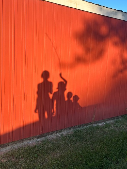 Shadows of kids on side of barn
