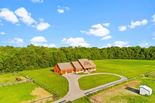 A farmhouse Airbnb in Indiana, nestled on an expansive horse farm, surrounded by lush greenery in the backdrop.