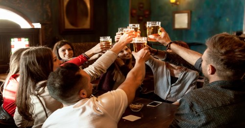 group of millennials people celebrating in a pub drinking beer and eating snacks