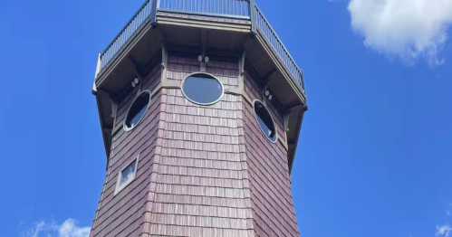 Unique shingle-sided lighthouse Airbnb near Burtrum, MN, with porthole windows and a rooftop observation deck.