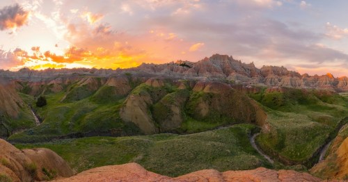 overlooking grassy fields and mountains with a sunset in the background in north dakota