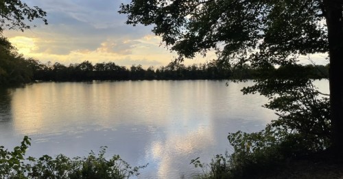 A New Jersey fishing lake reflects the sunset and sky.