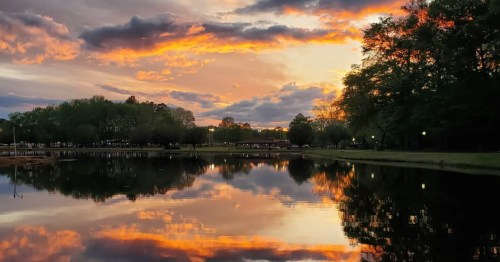 A sunset hike in Alabama leads to a peaceful lake reflecting the sky's sunset.