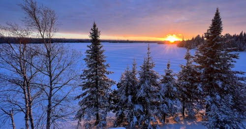 An orange sunset over frozen Poplar Lake in winter in Minnesota.