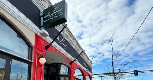 The Local West End Irish Pub exterior sign hangs on the red and black facade in St. Louis Park, MN.