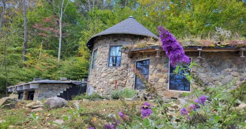 Exterior of The Tower at Underhill with stone landscaping and purple butterfly bushes in the yard.