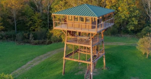 An exterior shot of the Slateville Retreat Tower Airbnb in Granville, New York. The tower is surrounded by tall trees.
