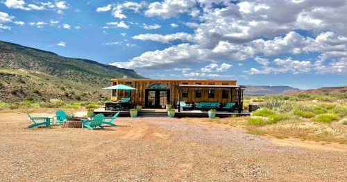 tiny utah cabin stationed on a trail with grass in the background and cotton clouds hanging in the sky
