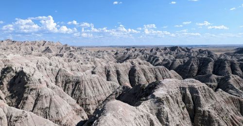 A landscape of rock formations under blue sky and light clouds.