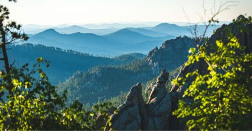 A landscape of rolling hills, rock formations, and greenery.