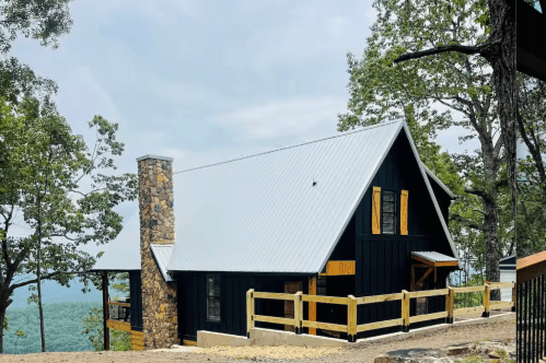 Black-sided cabin with a wooden deck overlooking a valley in Alabama