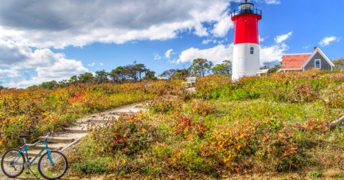 A red and white lighthouse on a grassy hill with a blue bicycle in the foreground, Nauset Light, Eastham, Massachusetts.