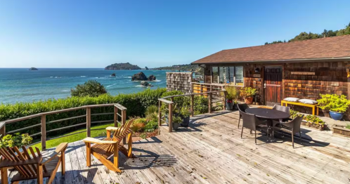 exterior photo of a surfside cabin with an outdoor deck and the ocean in the background