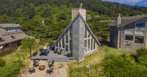 an a-framed lighthouse with a brick pillar in the center on the ocean coast of oregon