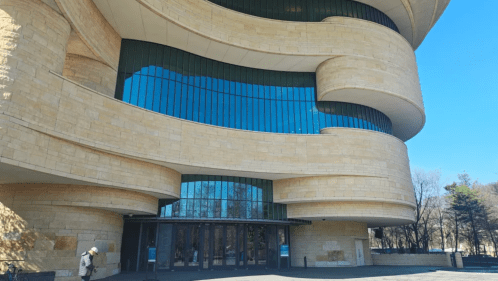 The facade of the Smithsonian National Museum of the American Indian, a towering building with a sandstone exterior.