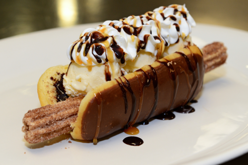 A close up shot of the Churro Dog -- a churro inside a donut topped with froyo, chocolate and caramel
