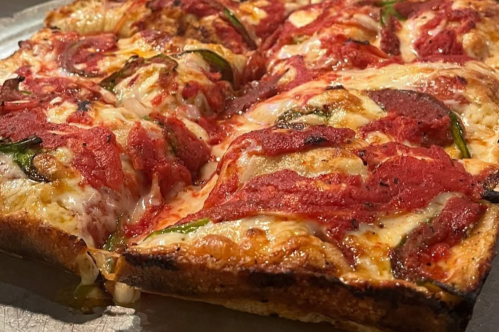 Close-up of deep dish pizza with toppings, tomato sauce, and crisp crust
