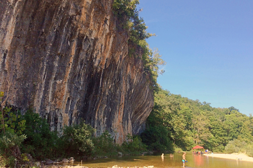 The towering bluff of Echo Bluff State Park rises over the waters of Sinking Creek.