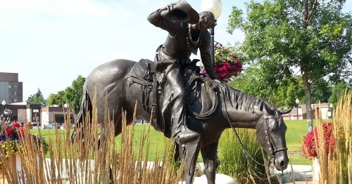 A dynamic bronze statue of a cowboy tipping his hat while on horseback in downtown Sheridan, Wyoming.