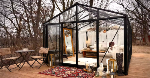 A cozy stargazing glass house Airbnb in Afton, MN, with a queen bed, wooden deck, and outdoor patio furniture.