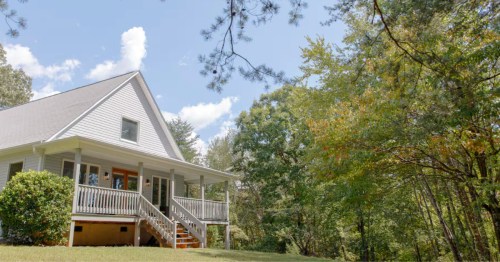 A white cabin in South Carolina nestled along the woods.