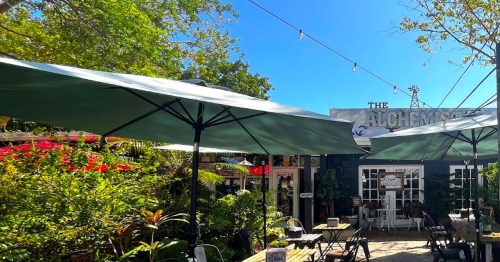 Flowers and umbrellas decorate the shaded patio at the Alchemist Cafe in Wilton Manors, FL.