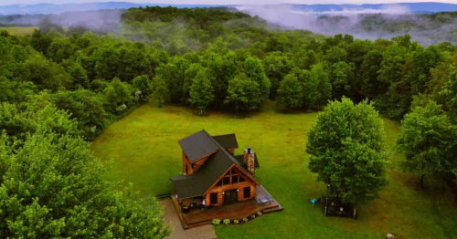 A drone view of a cabin in West Virginia surrounded by a forest.